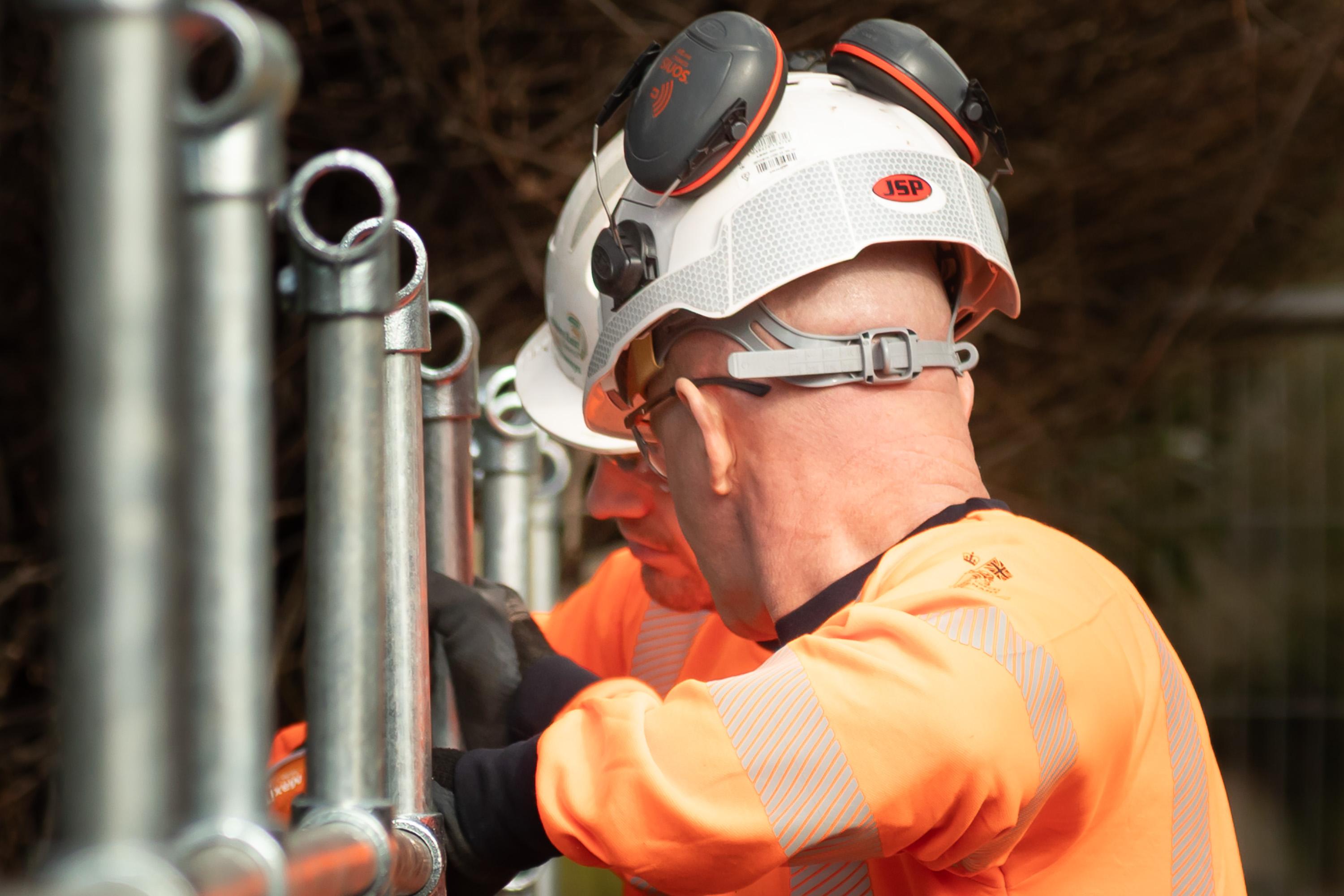 Two Ringway Jacobs highways operatives installing metal height restriction framework on existing bridge structure in Cheshire.
